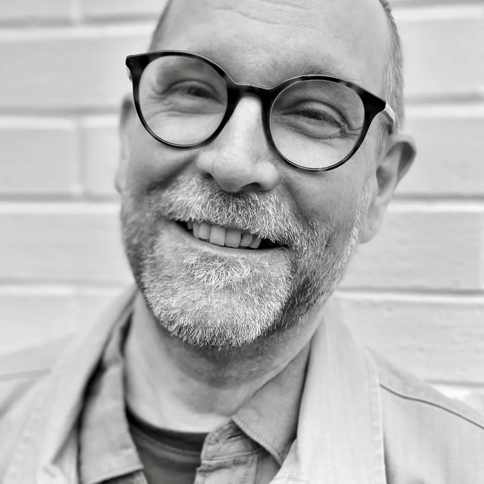 Smiling portrait of Duncan in black and white against light wall